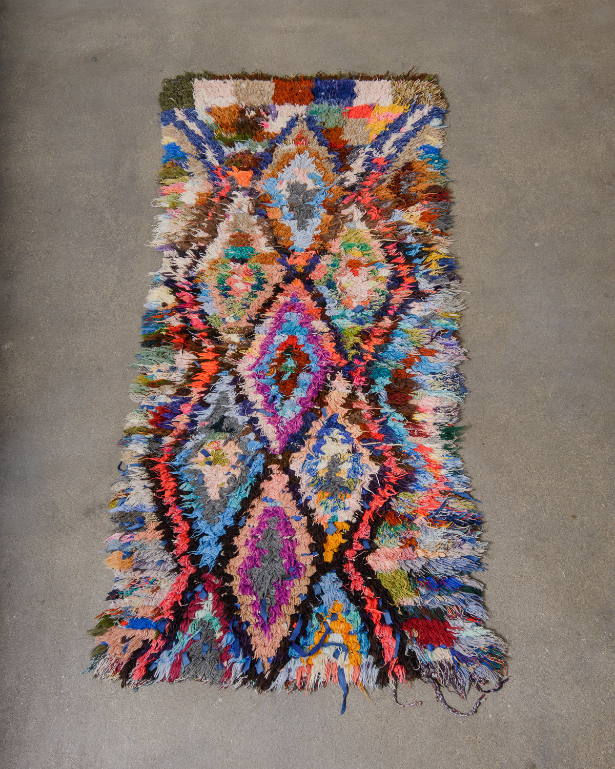 Multicolored woven rug with geometric pattern on a gray concrete floor